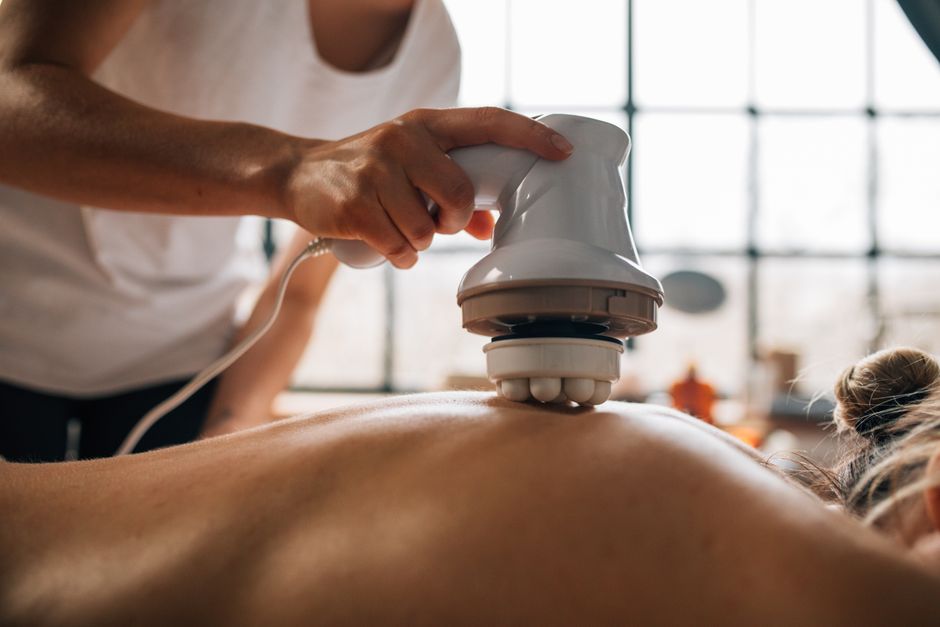 Een persoon die een massageapparaat gebruikt voor het herstel van vermoeide benen na een training.